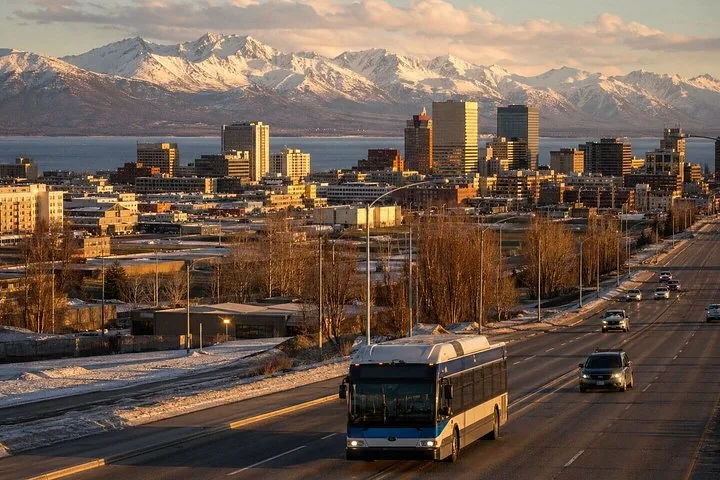 A city skyline featuring high-rise buildings and a bus on a road